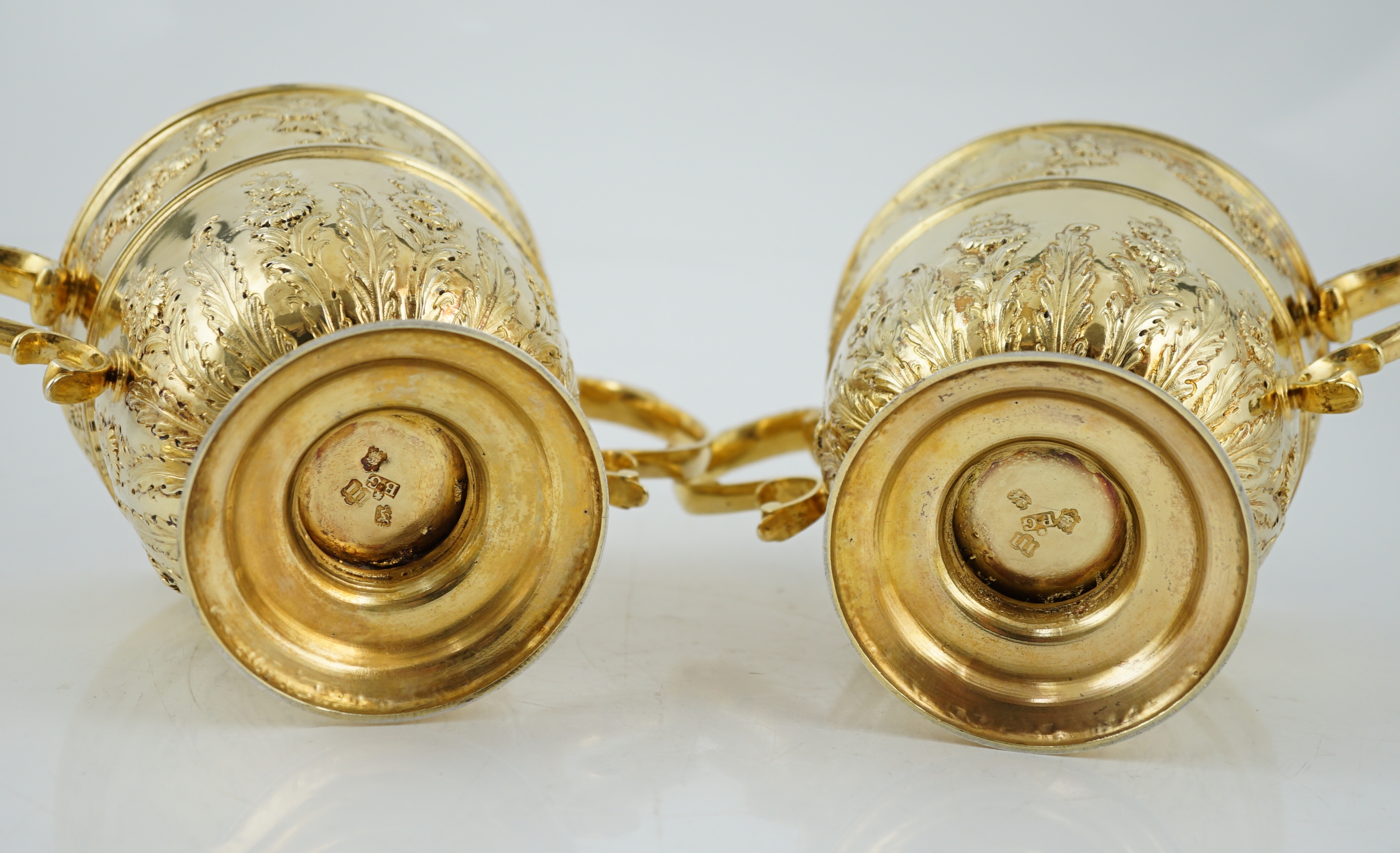 Benacre Hall, Suffolk. A good pair of George II embossed silver gilt two handled pedestal cups and covers, by Benjamin Gignac